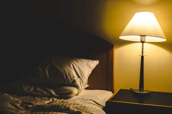 Leeres Bett mit eingeschalteter Lampe
